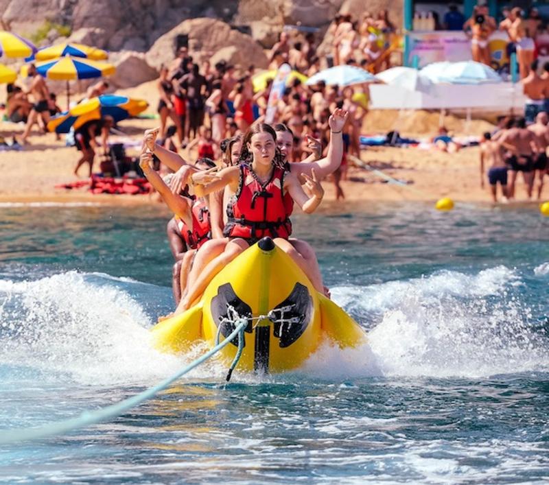 Meisjes worden vooruitgesleept met een banaan op het water tijdens een zonvakantie