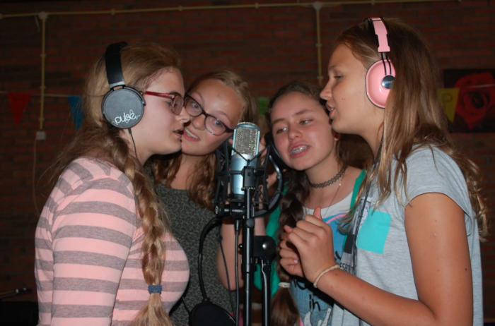 Meisjes zingen in microfoon op theaterkamp.