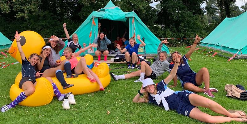 Meiden chillen voor de tenten tijdens een hockeykamp