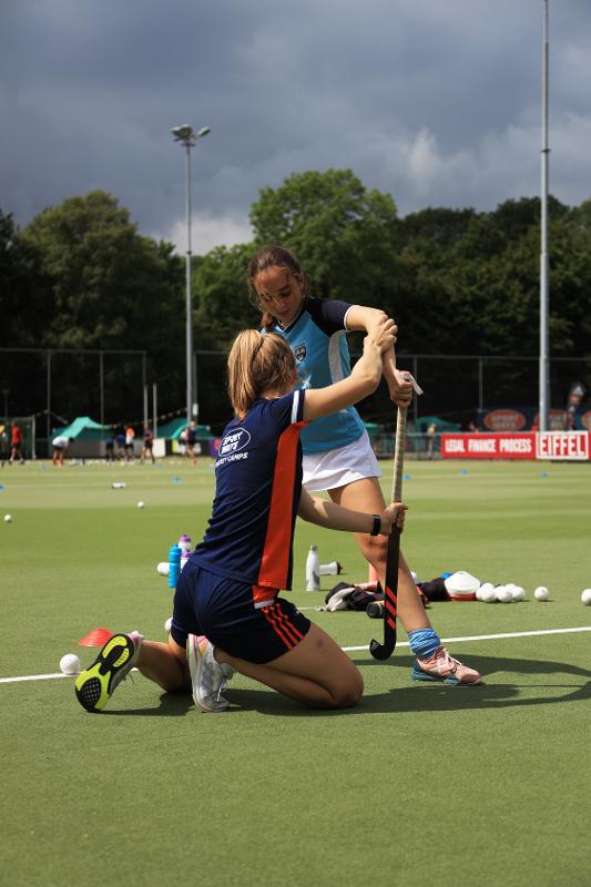 Meisje krijgt hockeyles tijdens een hockeykamp
