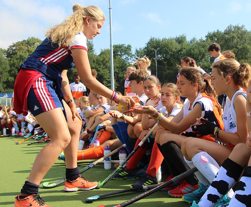 meisje deelt iets uit tijdens de training op zomerkamp antwerpen hockeykamp