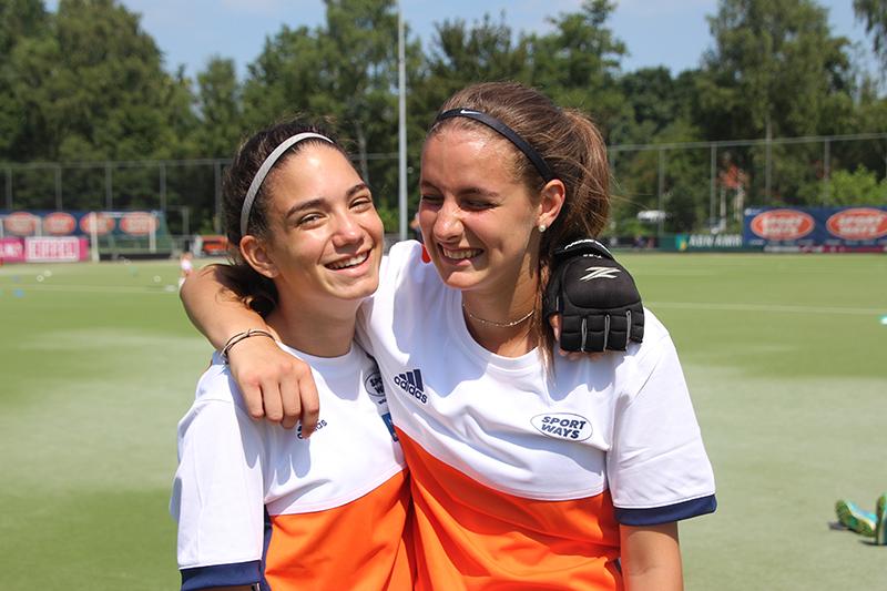 twee meisjes lachen op het veld op zomerkamp antwerpen hockeykamp