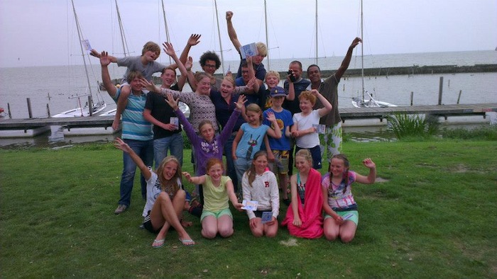 Deelnemers en begeleiders poseren lachend voor de camera op zeilkamp Haarlem