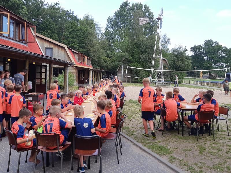 jongens in voetbalshirt eten buiten op voetbalkamp overijssel