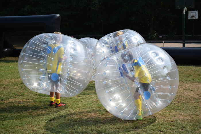 Jongeren spelen bubblevoetbal op voetbalkamp.