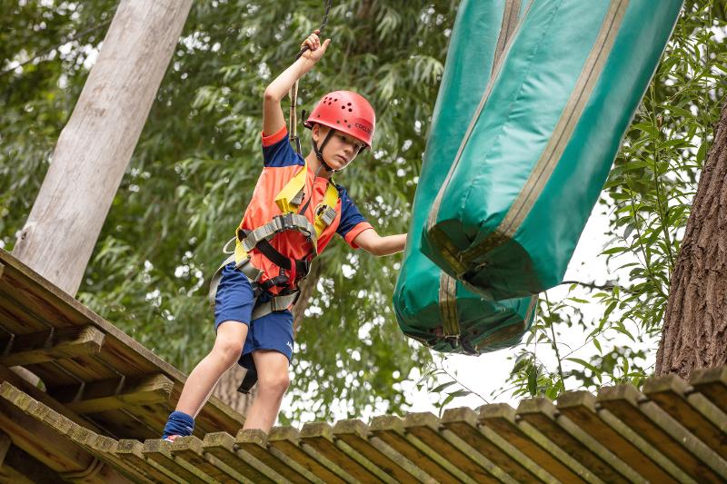 Een jongen tijdens een summer camp klimt in een bos