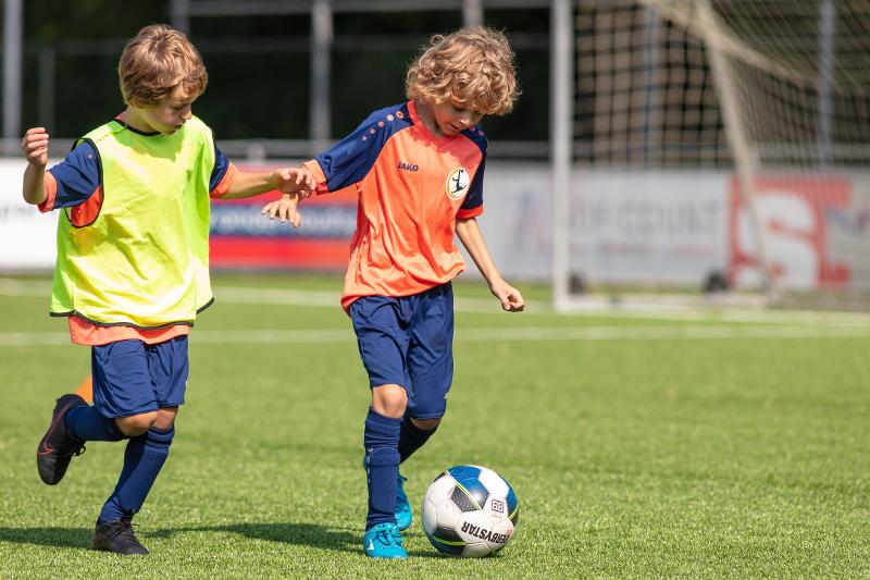 twee jongetjes voetballen op het veld op voetbalkamp overijssel