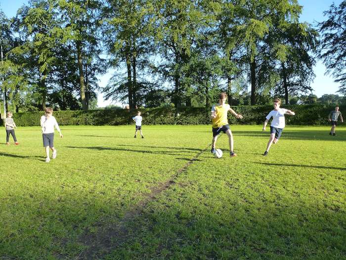 jongens voetballen buiten op het veld op jeugdvakantie