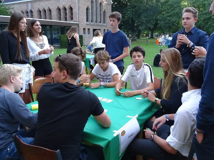 jongeren zitten buiten aan tafel een kaartspel te spelen op jeugdvakantie