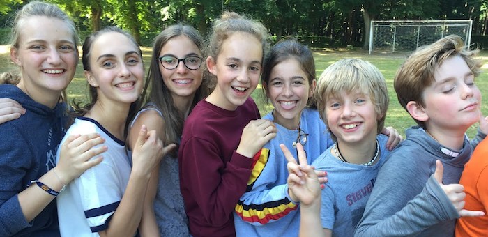 jongeren poseren voor een groepsfoto op het sportveld op jeugdvakantie