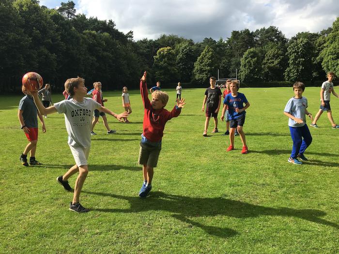 jongetjes spelen handbal op het sportveld buiten tijdens jeugdvakantie