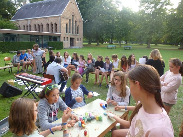 deelnemers zitten buiten aan tafel en volgen een workshop