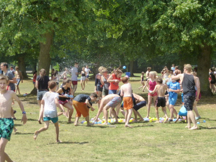 jongeren spelen met water op het grasveld op jeugdvakantie
