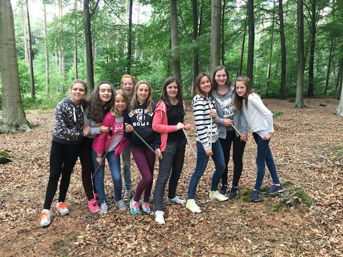 meisjes poseren voor groepsfoto tijdens spel in het bos op jeugdvakantie