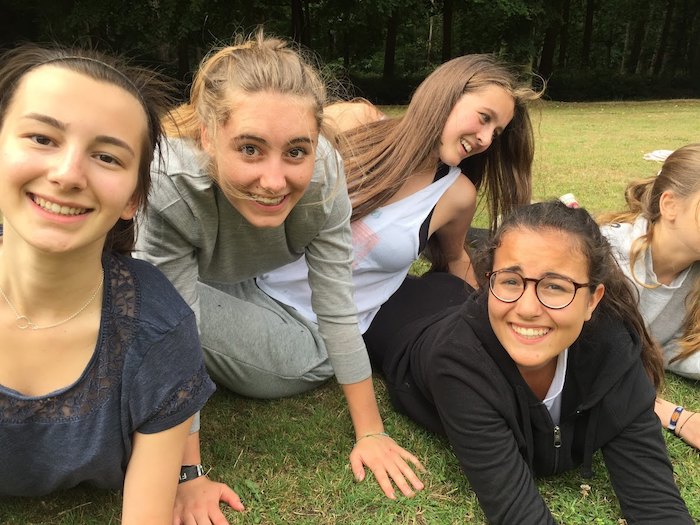 meisjes kijken naar de camera terwijl ze op het grasveld liggen op jeugdvakantie