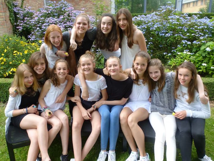 Meisjes poseren voor een klassenfoto bij bloemetjes op jeugdvakantie