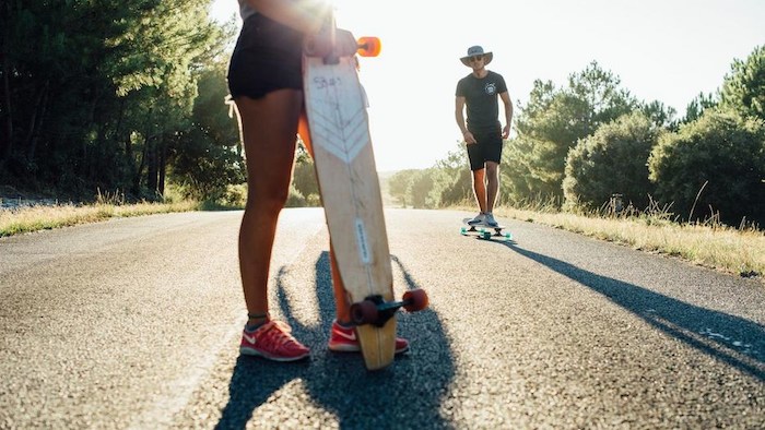 meisje houdt longboard vast op de weg op surfkamp jeugd in frankrijk