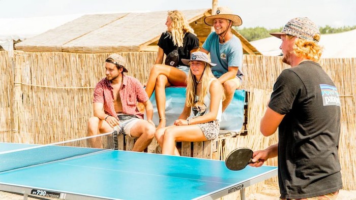 jongeren kijken jongen die aan het tafeltennissen is op surfkamp jeugd in frankrijk