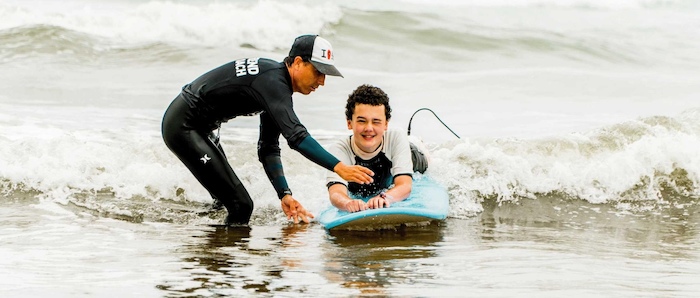 Surfinstructeur helpt jongen met techniek op de surfplank tijdens surfkamp 14 jaar
