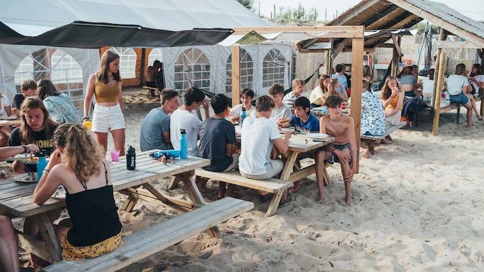 Deelnemers van surfkamp 14 jaar eten samen onder tent
