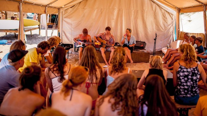 Groep jongeren maken muziek in een tent tijdens taalkamp Frans