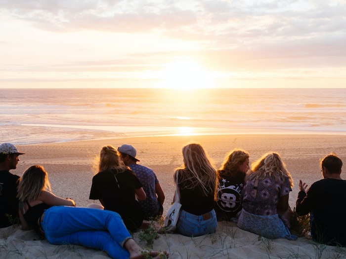 Een groepje deelnemers zit op het strand tijdens een groepsreis Frankrijk. 