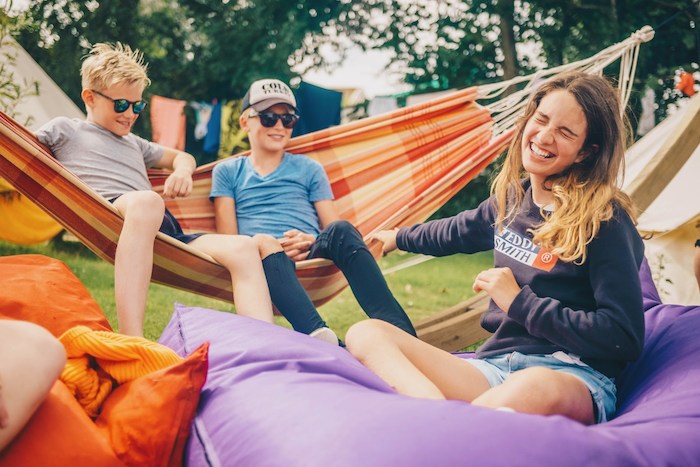Een groep jongeren zitten in een hangmat tijdens een summer camp den haag en lachen