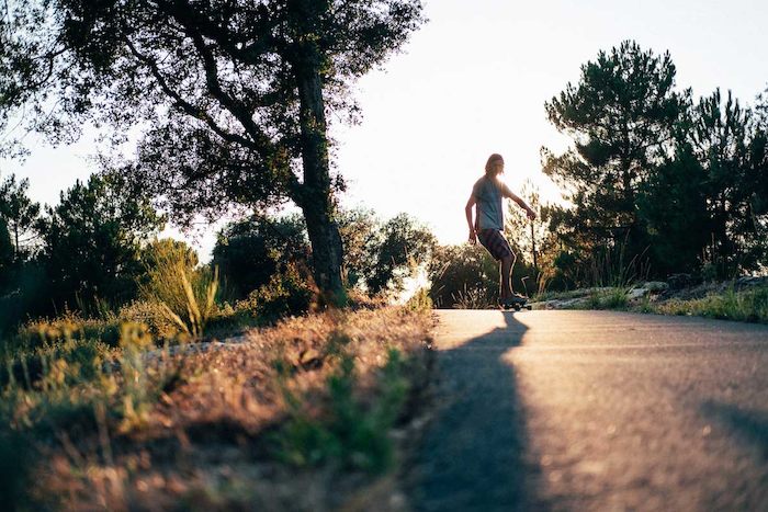 Een jongen in Den Haag is aan het longboarden tijdens zonsondergang tijdens zijn Summer Camps