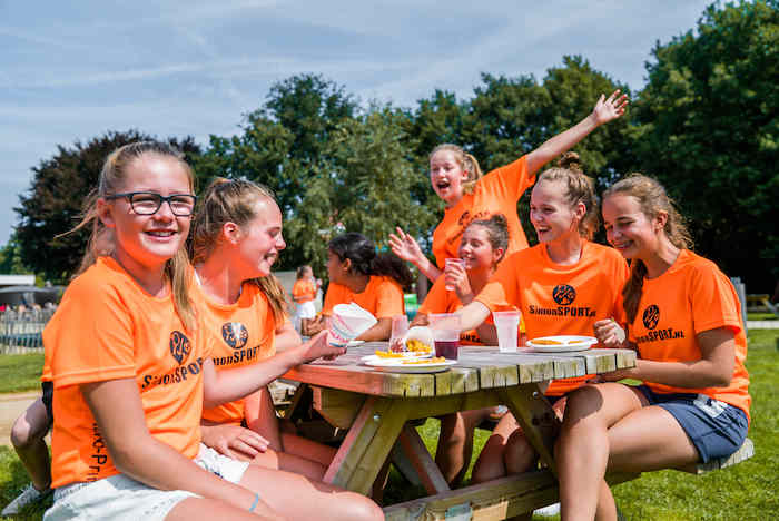 Jongeren lunchen samen op het hockeykamp in Noord-Brabant in de zomer.