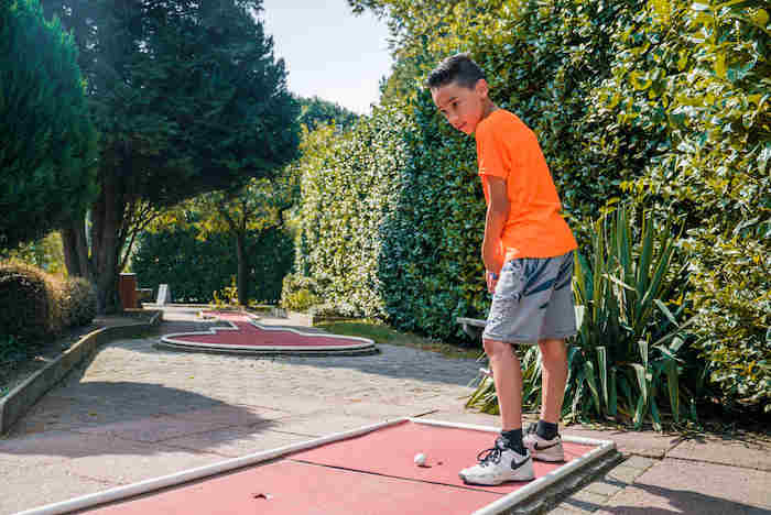 Jongen speelt mini-golf op het multi sportkamp in Noord-Brabant tijdens de zomer.