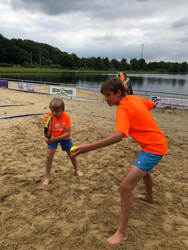 twee jongens houden bal en racket vast op het zand op padelkamp noord-brabant zomer