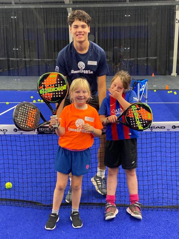 twee meisjes met trainer voor het net op padelkamp noord-brabant zomer