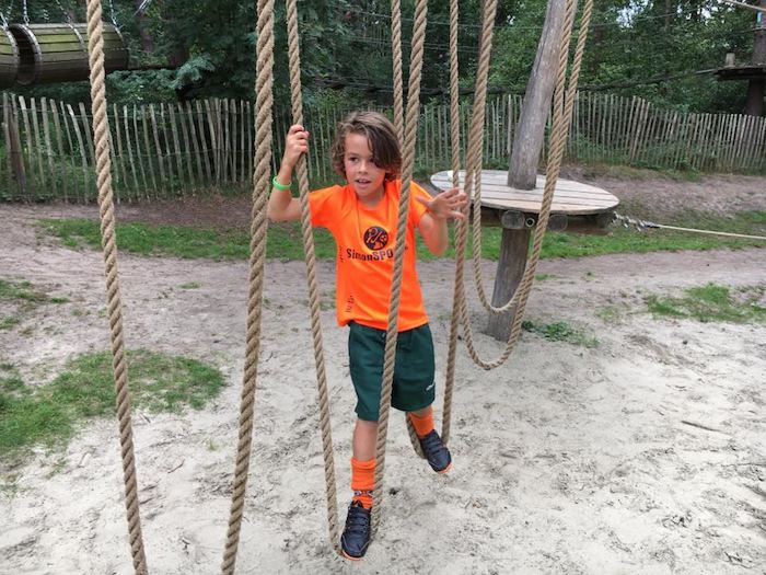 Jongen op het touwenparcours op het tenniskamp in Brabant in de zomer.