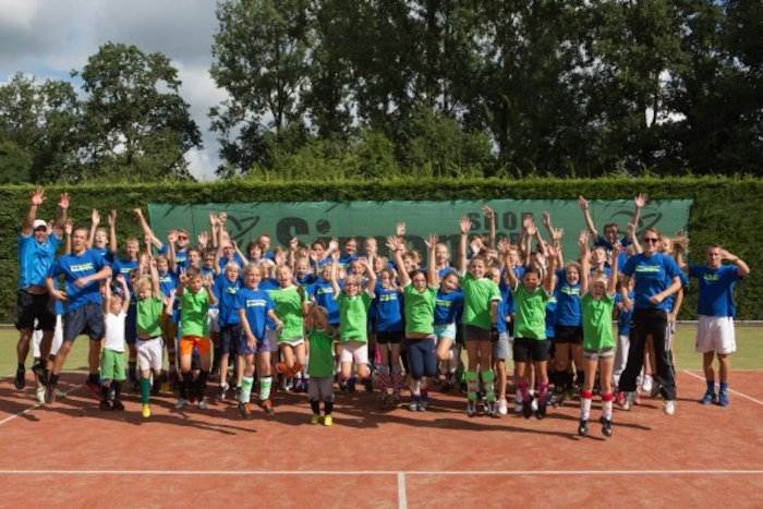 Jongeren poseren voor de groepsfoto op het tenniskamp in Brabant in de zomer.