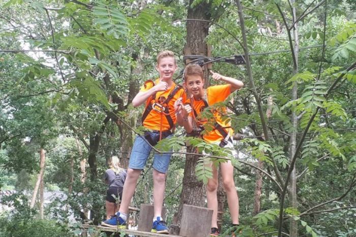 Jongens klimmen in bomen op het tenniskamp in Brabant in de zomer.