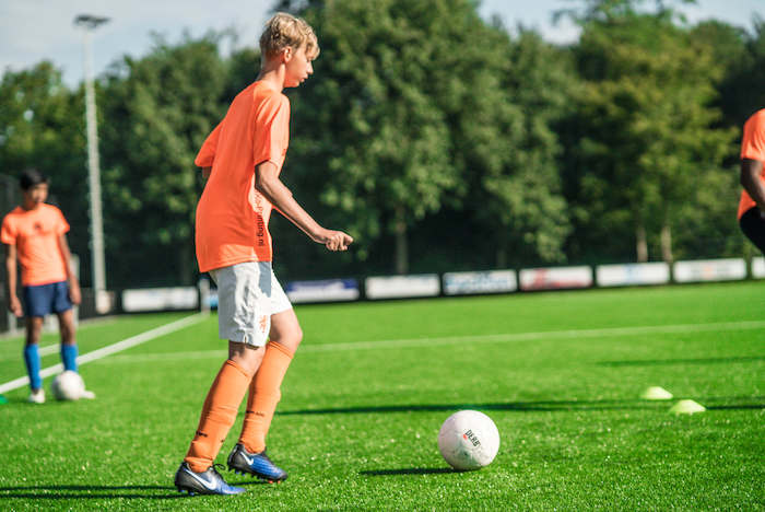 Jongen geeft een pas Jongens aan het muurklimmen op voetbalkamp in Brabant tijdens de zomer.