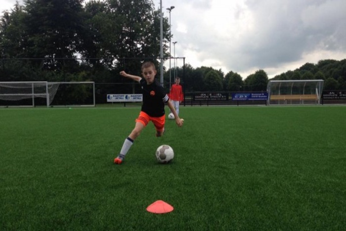 Jongen loopt met een voetbal Jongens aan het muurklimmen op voetbalkamp in Brabant tijdens de zomer.