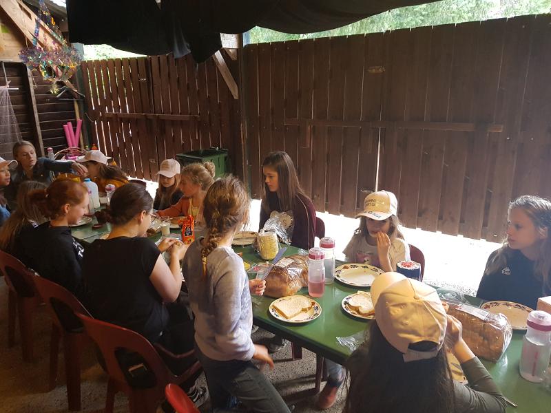 meisjes zitten aan lange eettafel voor de lunch op danskamp gelderland zomervakantie girl camp