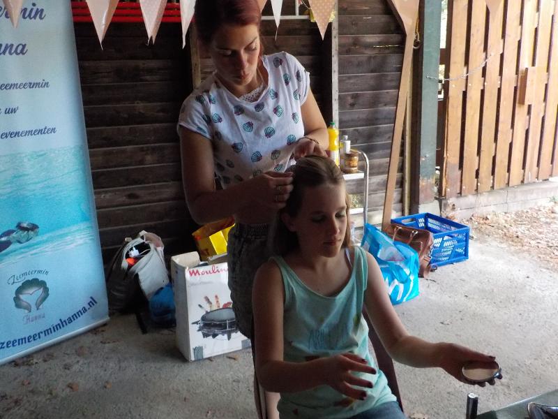 begeleidster maakt vlecht in haar van meisje op meiden zomerkamp nederland girl camp
