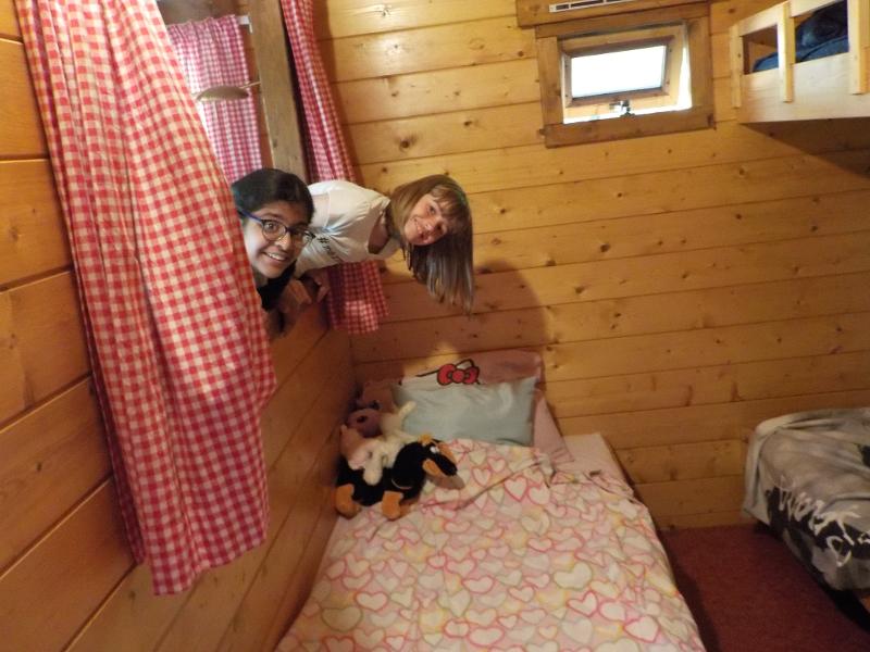 meisjes hangen via het raam naar binnen bij slaapkamer op meiden zomerkamp nederland girl camp