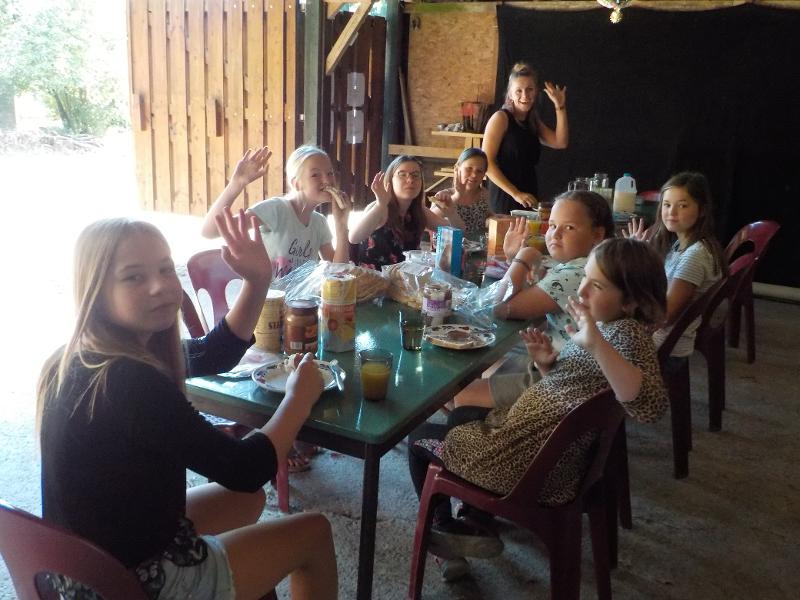 meisjes zwaaien naar camera tijdens ontbijt op meiden zomerkamp nederland girl camp