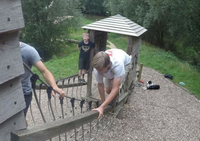 Jongen klimt over parcours op een goedkope jongerenvakantie