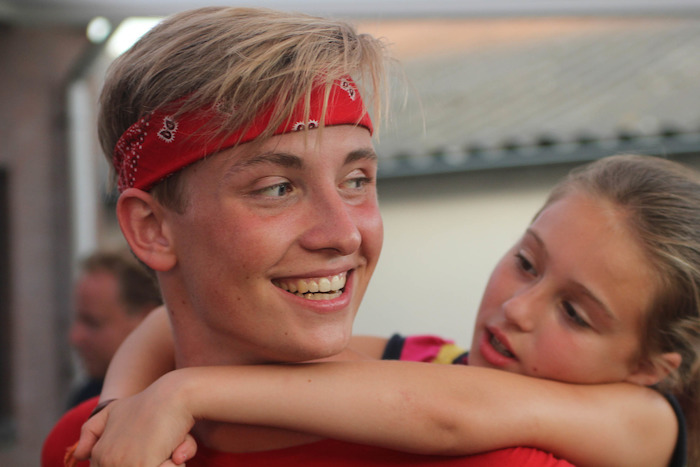 Een jongen met een rode bandana lacht tijdens het musicalkamp in Noord-Brabant in de zomer.