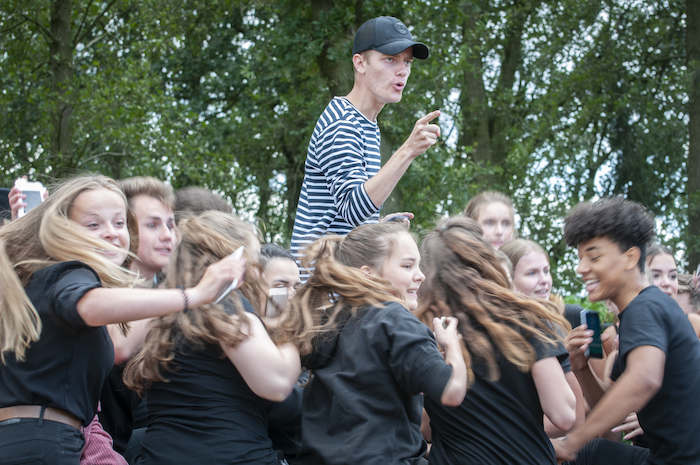 Een jongen boven een groep jongeren tijdens het musicalkamp in Noord-Brabant in de zomer.