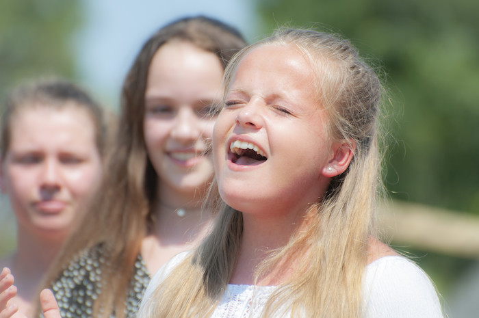 Een blond meisje zingt tijdens het musicalkamp in Noord-Brabant in de zomer.