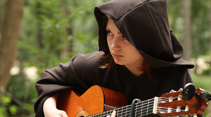 Meisje in zwarte cape speelt gitaar tijdens muziekkamp