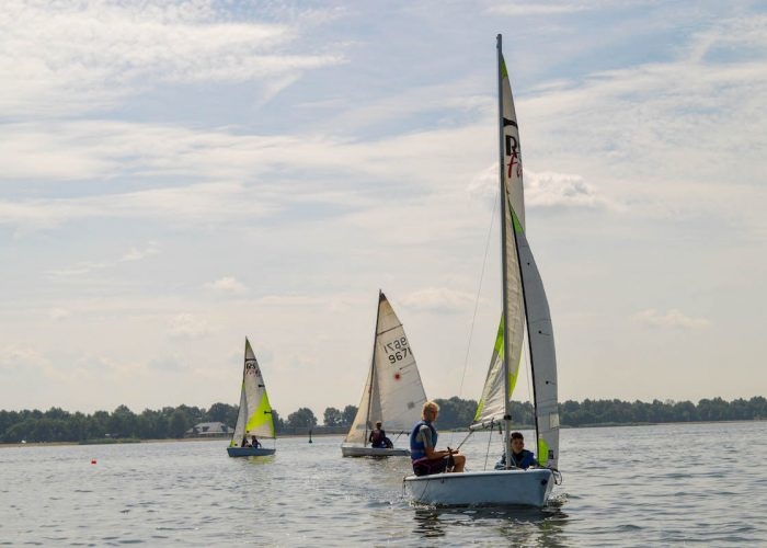 Kinderen en begeleider zitten in zeilboot tijdens een zeilkamp Amsterdam