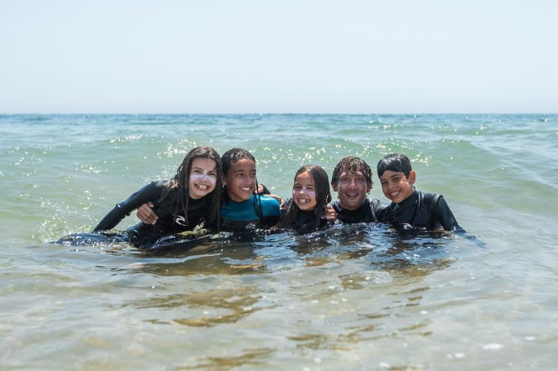 deelnemers aan jongerenreis surfen in het water
