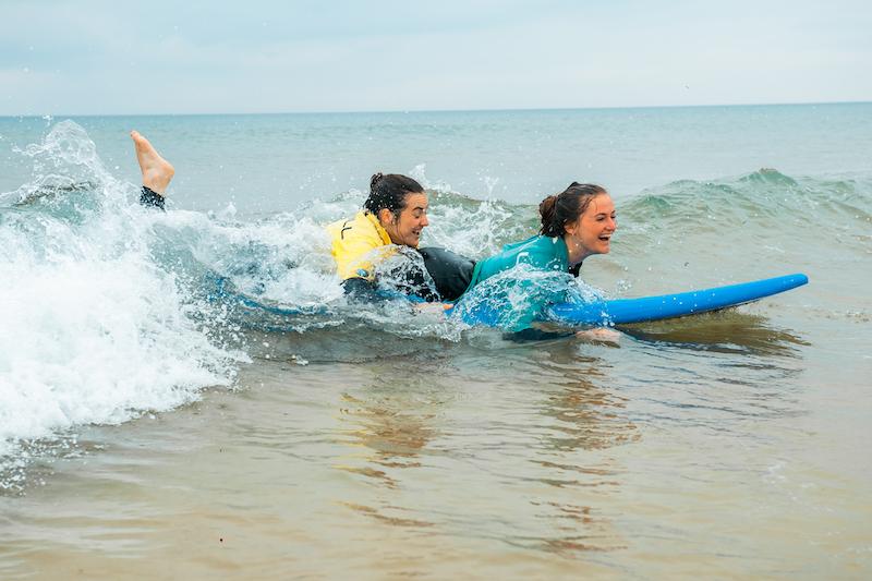 Jongeren zitten samen op een surfplank.