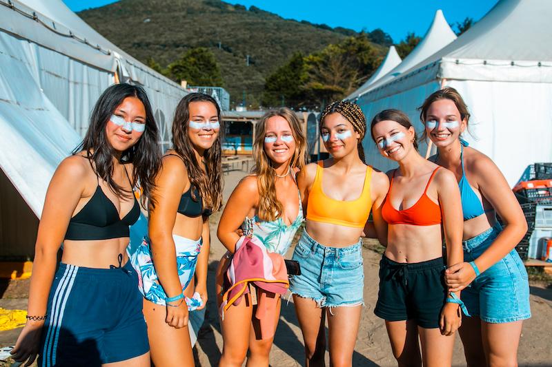 Meiden gaan samen op de foto op het surfkamp 18 plus en dragen allemaal sunblock.